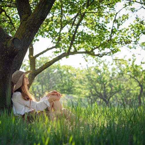 woman traveler with backpack and hat sitting in amazing forest, wanderlust travel concept, space for text, atmospheric moment. earth day
